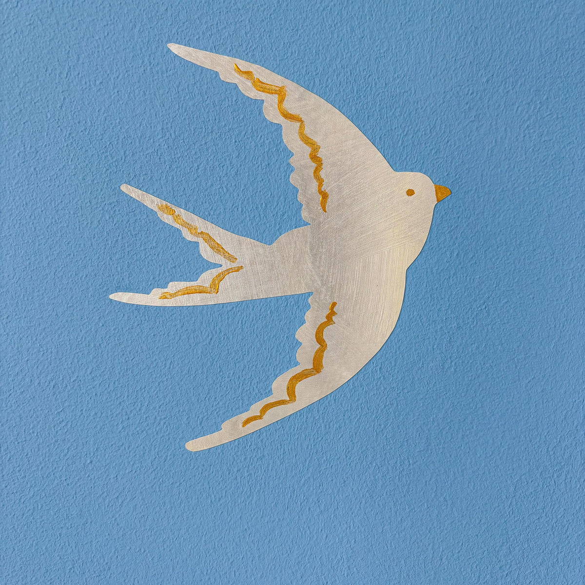 Håndmalet svale wall sticker i perlemor med guldbølger på blå væg