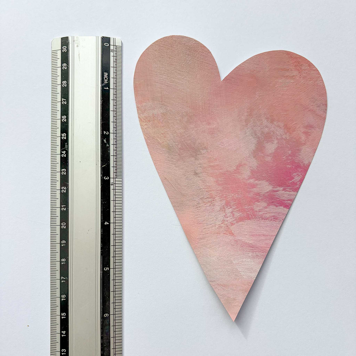 Et håndmalet lyserødt hjerte wall sticker vist ved siden af en tommestok som størrelsesreference - hjertet måler ca. 18 x 12 cm
