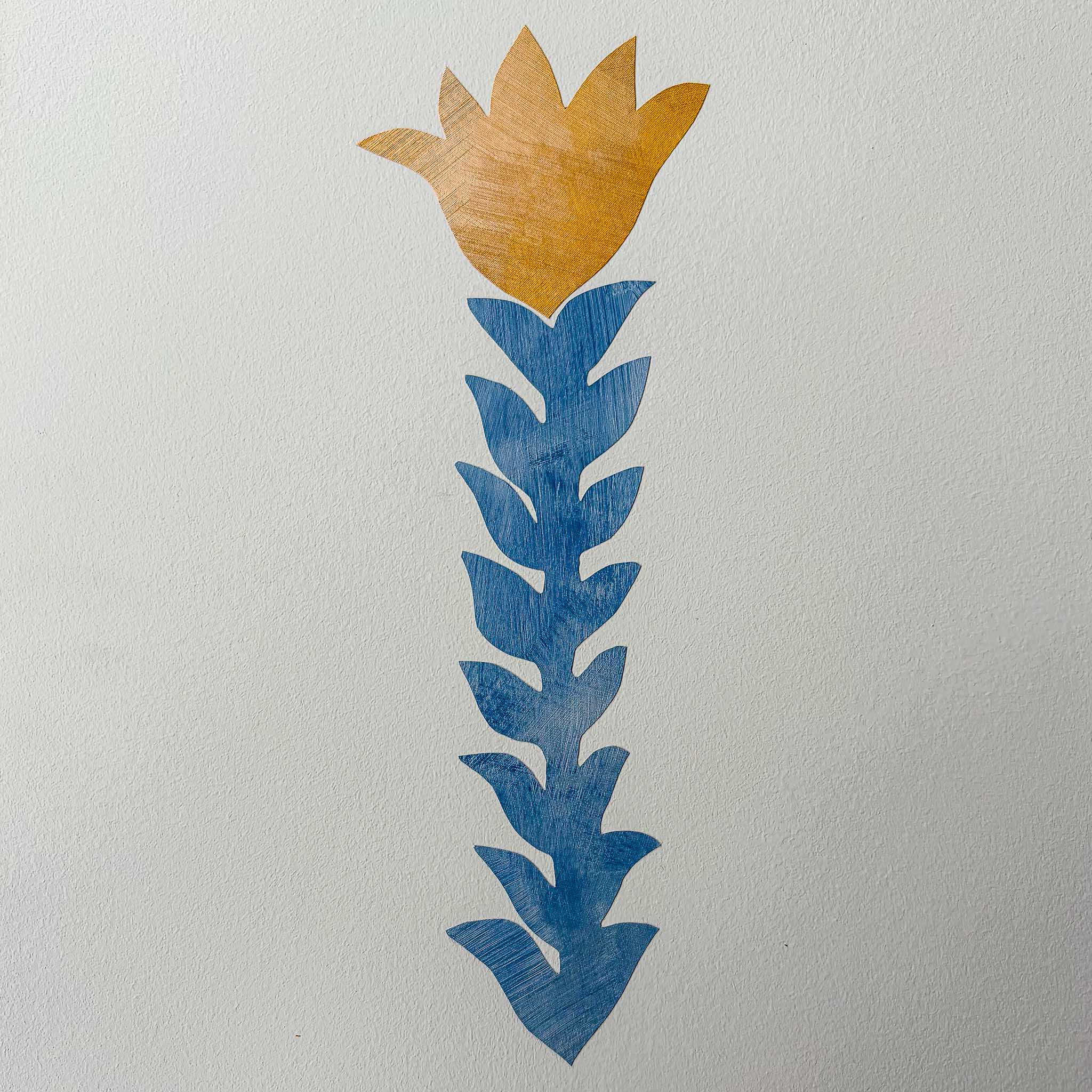 Håndmalet blomst og blad-motiv i guld og blå til vægmaleriet