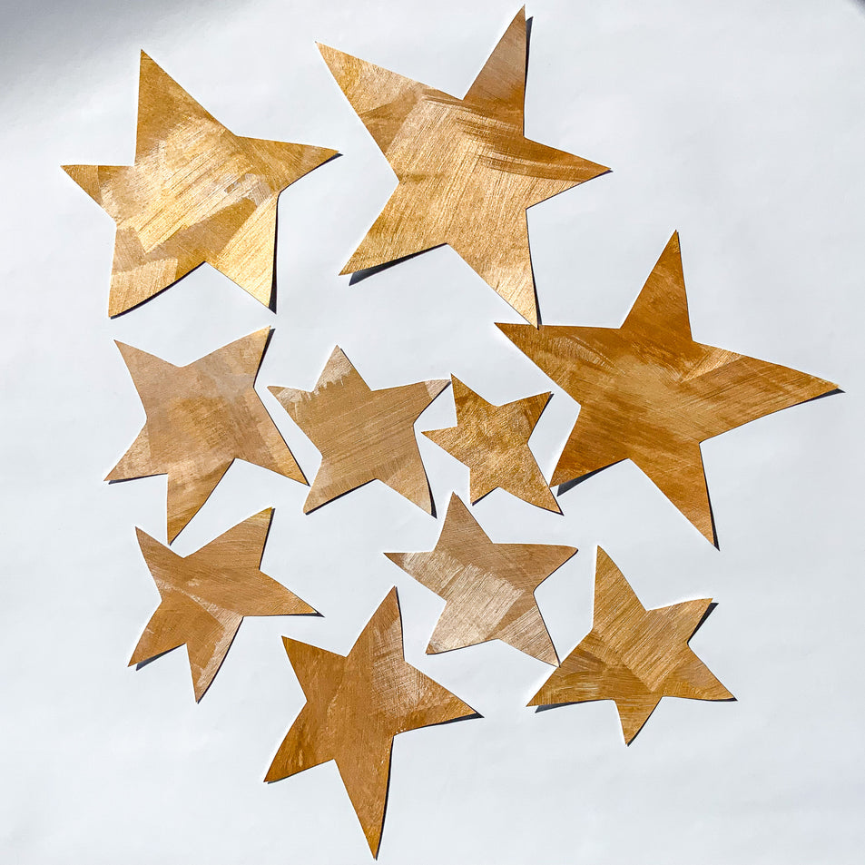 Nærbillede af håndmalede guld stjerne wallstickers til børneværelset fra Tonka Papers.