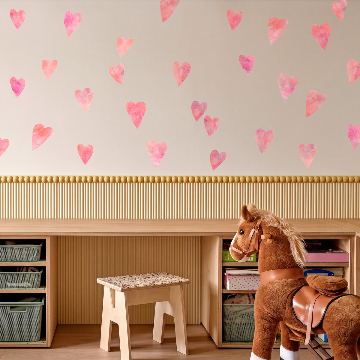 Lyserøde håndmalede hjerte wall stickers spredt på væggen over et legeværelse med opbevaringsreoler og en gåhest - flytbare hjerte-vægdekaler til børneværelse